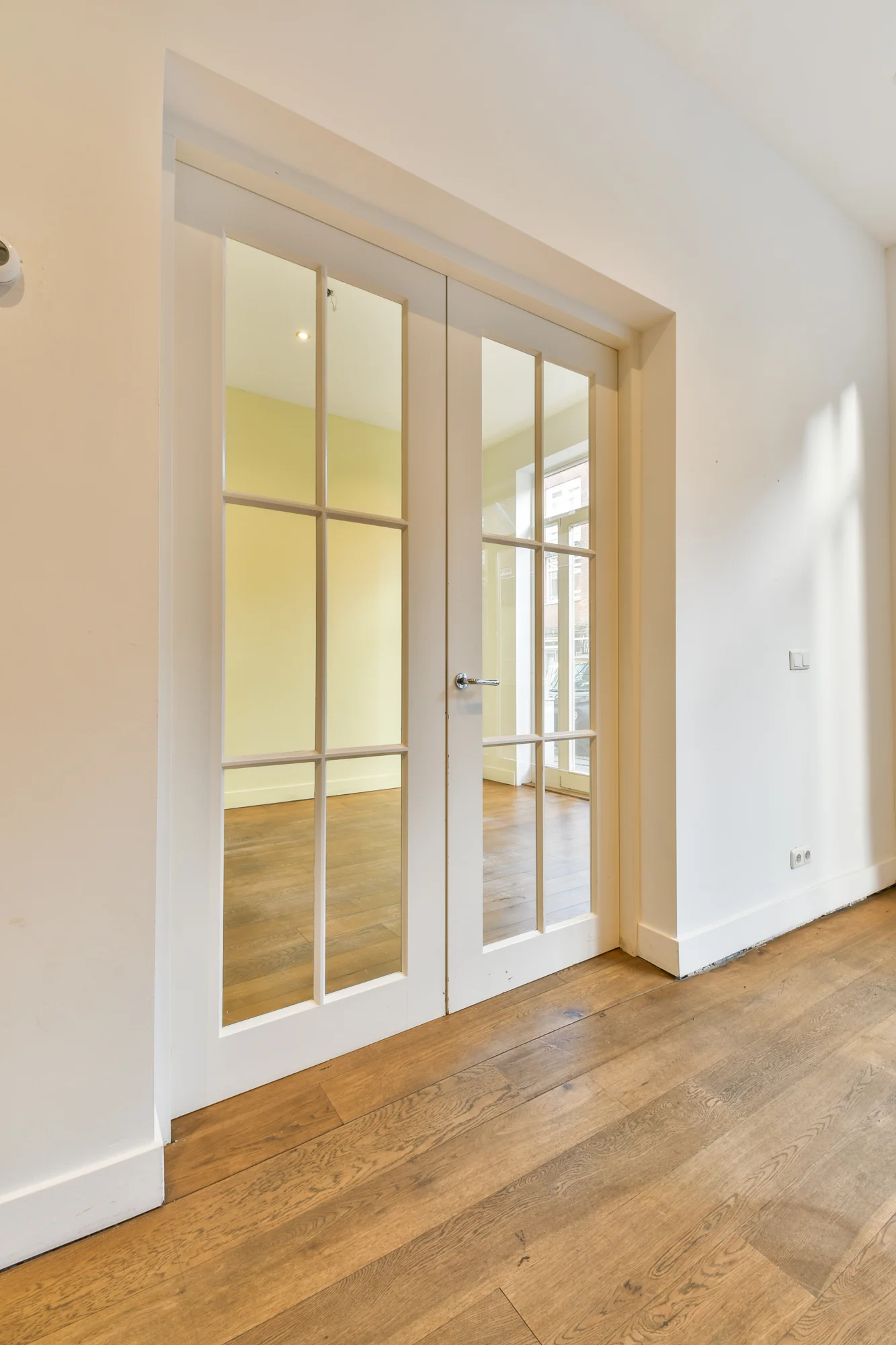 Witte dubbele glazen binnendeuren met roedeverdeling in een interieur met houten vloer in de Korte Schimmelstraat.
